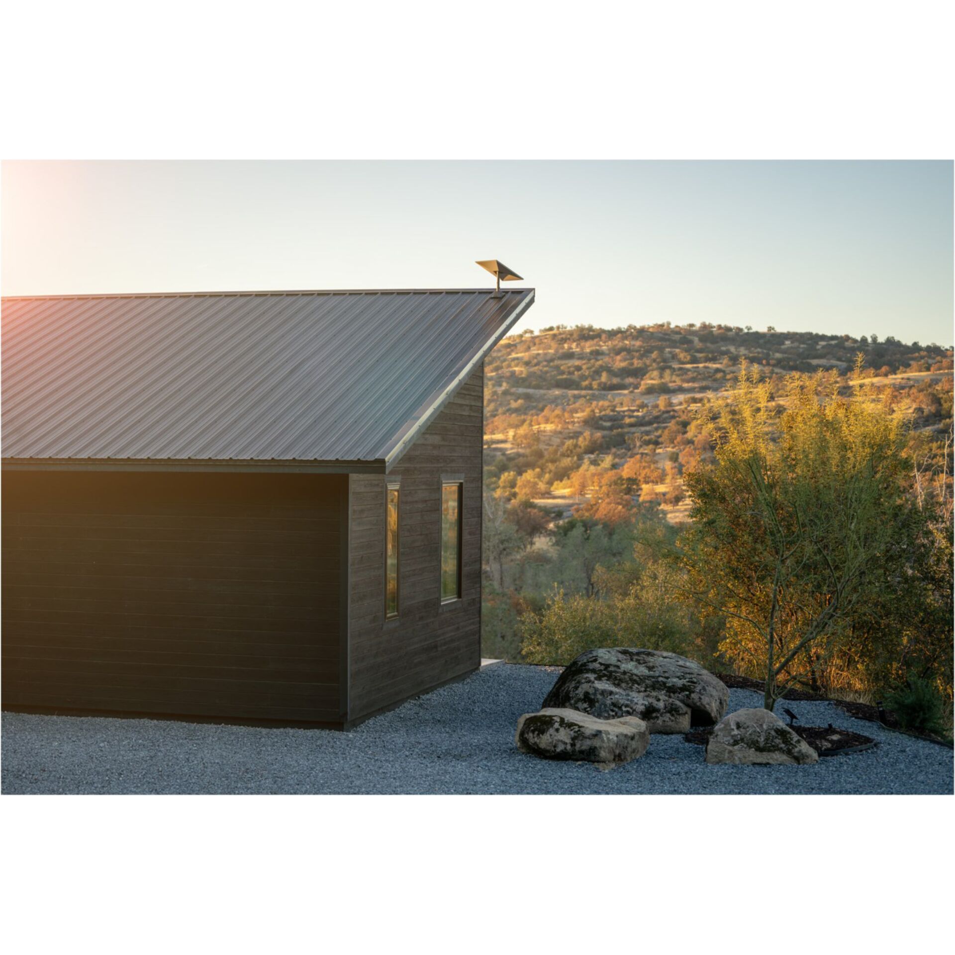 tiny house, wood siding, metal roof, windows, rock landscaping