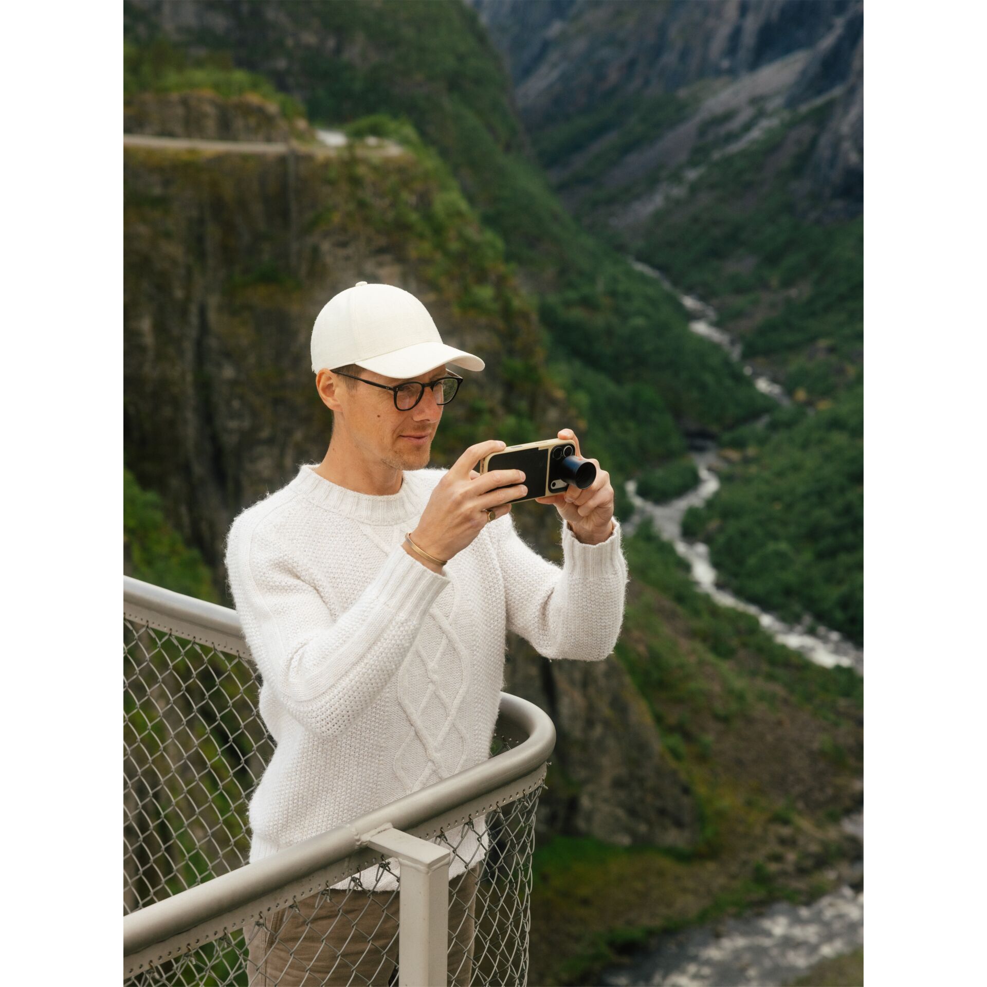 weißerPullover, Knitpullover, weißeMütze, Brille, Camcorder?