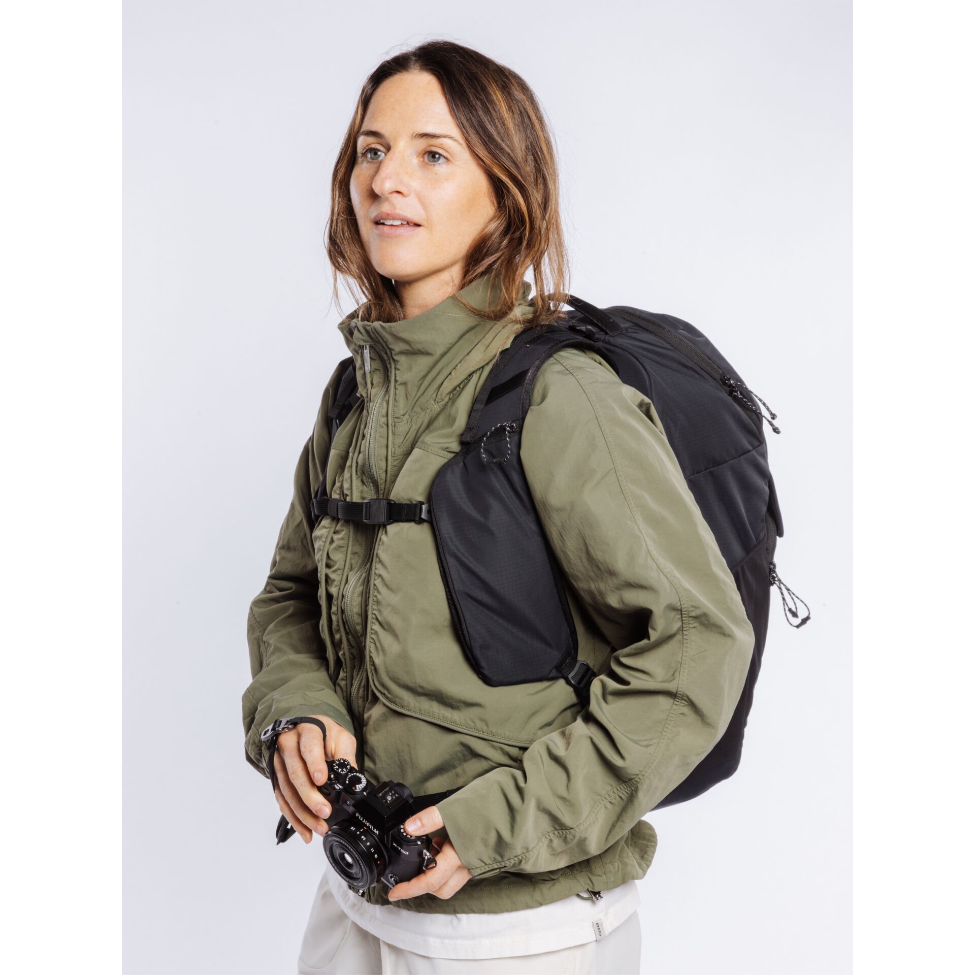 black backpack, camera, green jacket, hiking gear, pilot vest