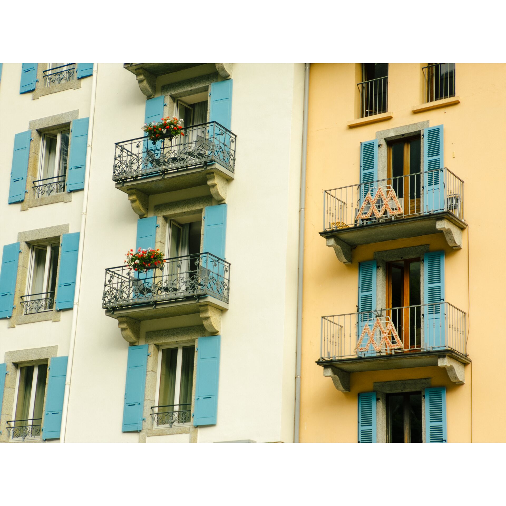 Balkone, bunte Fassade, blaue Jalousien, Blumentöpfe, Wohngebäude